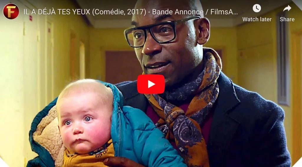 Screen grab from the french film "he even has your eyes", showing a white baby with a black man